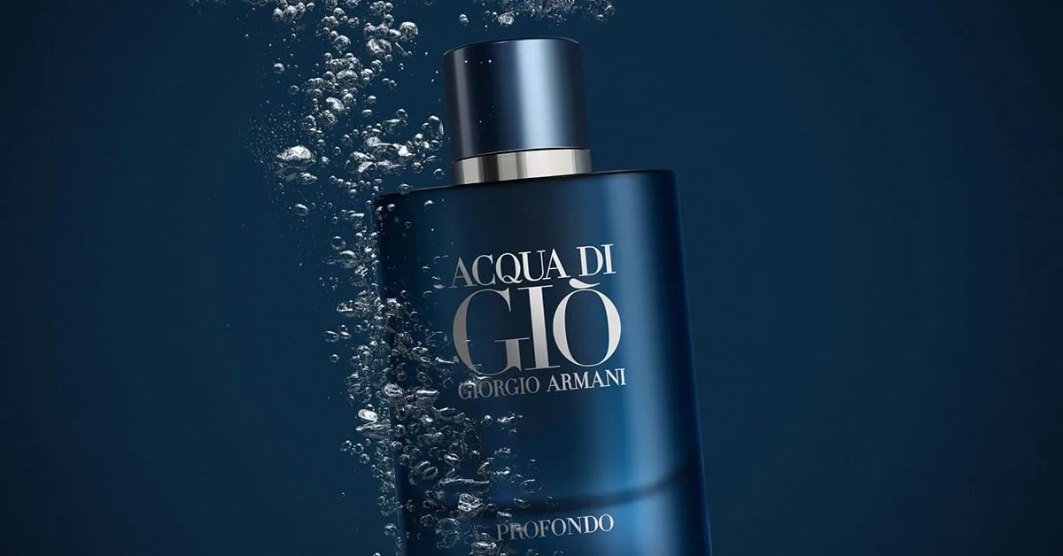 The deep-blue lacquered bottle tilted mid-plunge in dark water, a column of silver bubbles streaming up its flank