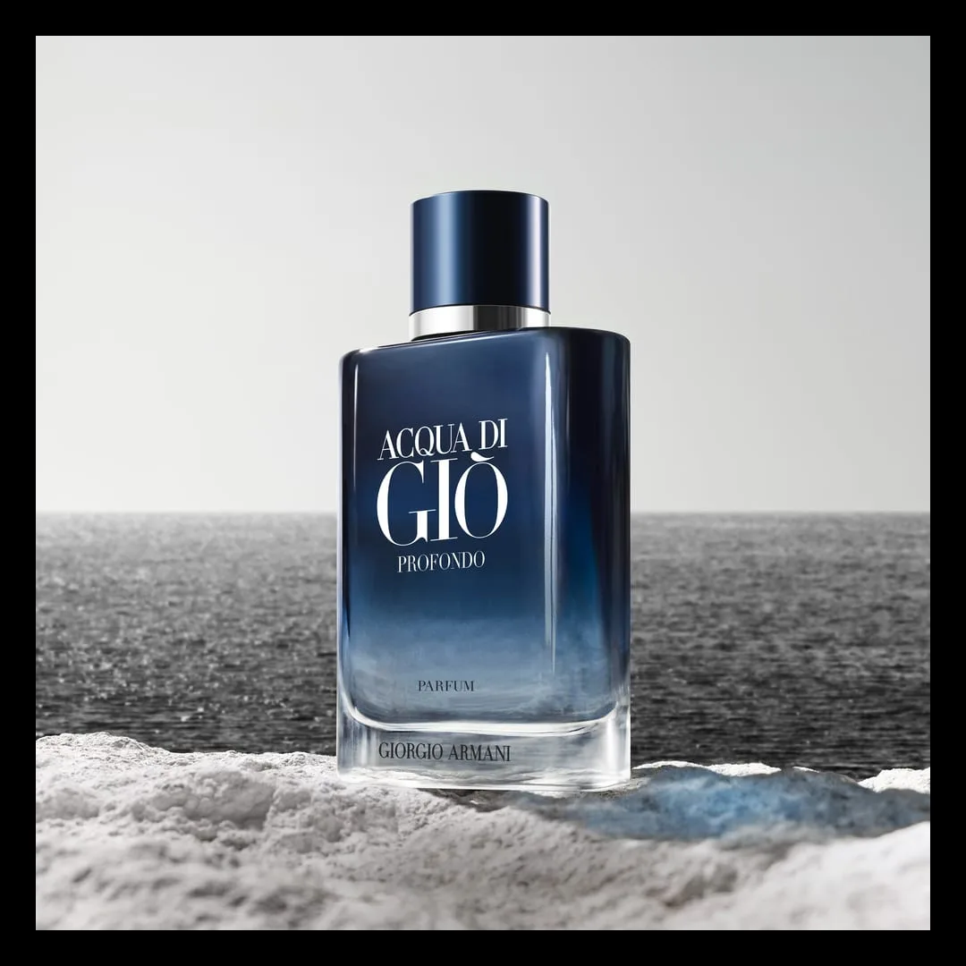 The Profondo Parfum flacon stands on a ridge of white sea-foam before a black-and-white ocean, its gradient blue glass the only colour in a monochrome sea