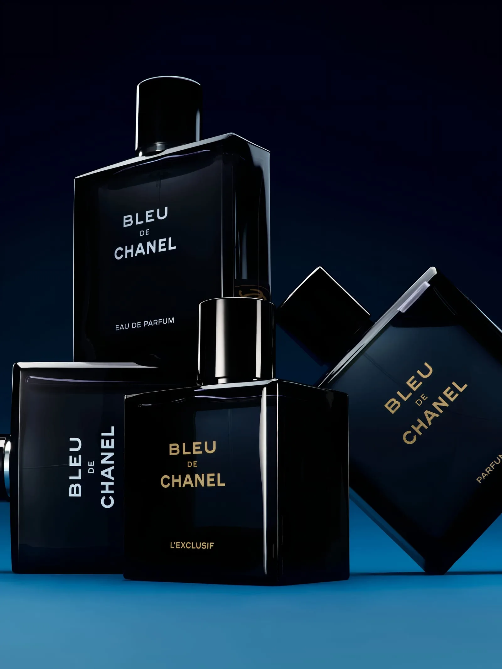 The Bleu de Chanel line stacked like dark monoliths on a deep blue gradient, the Eau de Parfum crowning the composition in silver-white lettering