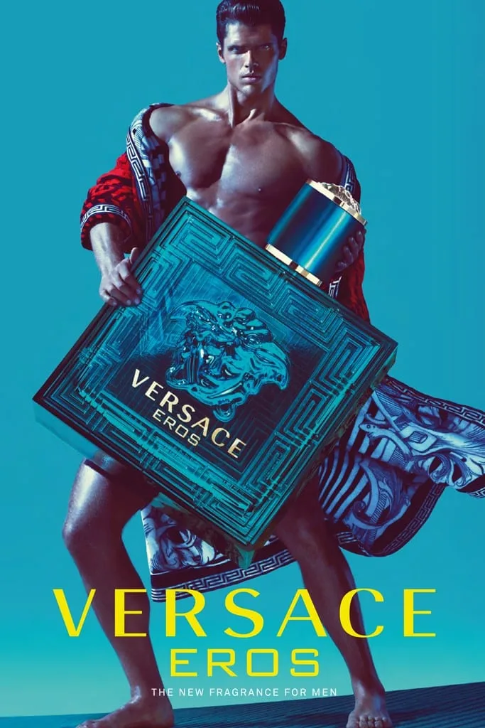 A modern Eros in a slipping Grecian-print robe clasps a colossal Eros flacon against a field of saturated turquoise, VERSACE EROS in yellow capitals beneath