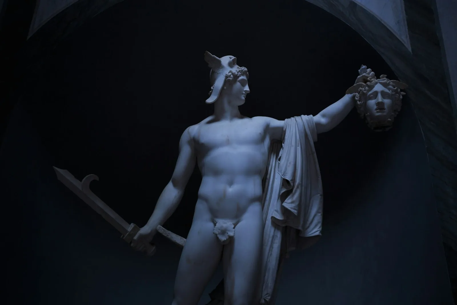 Canova's Perseus in a moonblue vault of shadow, the head of Medusa held out at arm's length — marble gone cold turquoise in the dark
