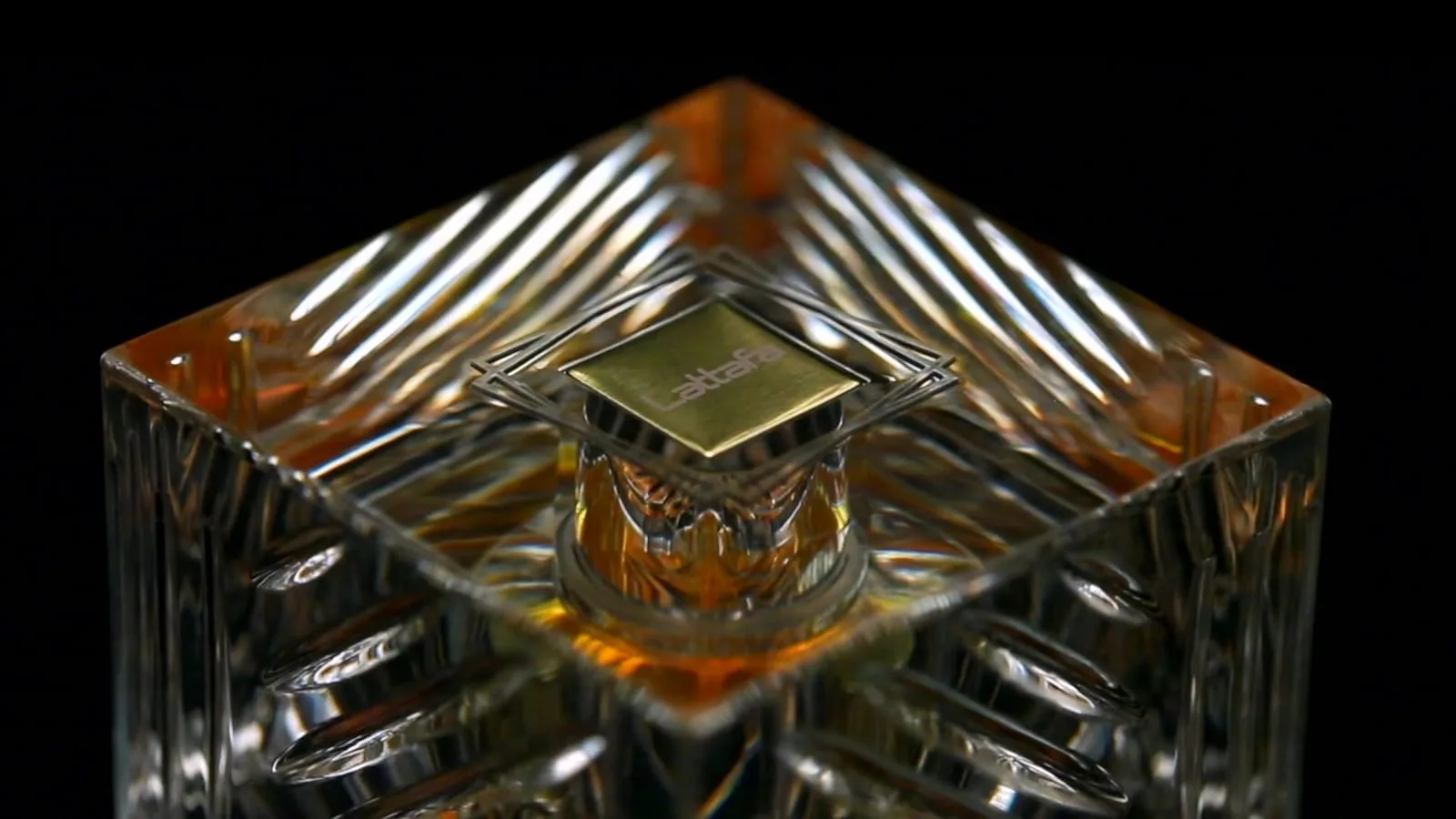 Seen from above against black, the crystal shoulders of the flacon splay outward like a star of cut glass, the small gold Lattafa plaque glinting at its centre